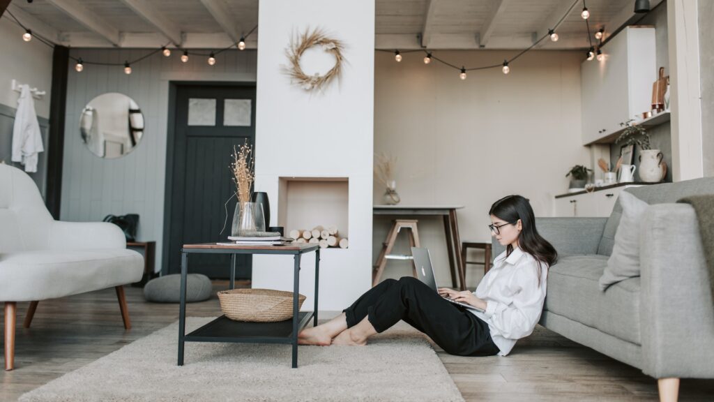 Home sellers researching the process of selling her home sitting on the floor in her living room