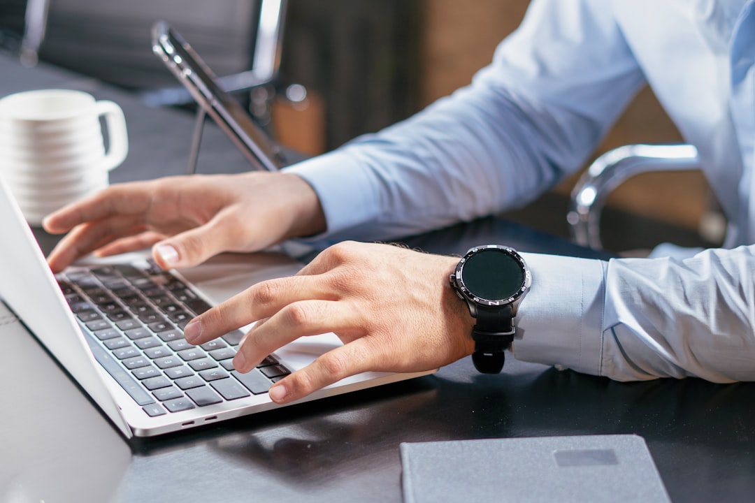 A focused real estate agent in a modern office works on a laptop displaying a high-quality property photo, symbolizing digital asset management and protection.