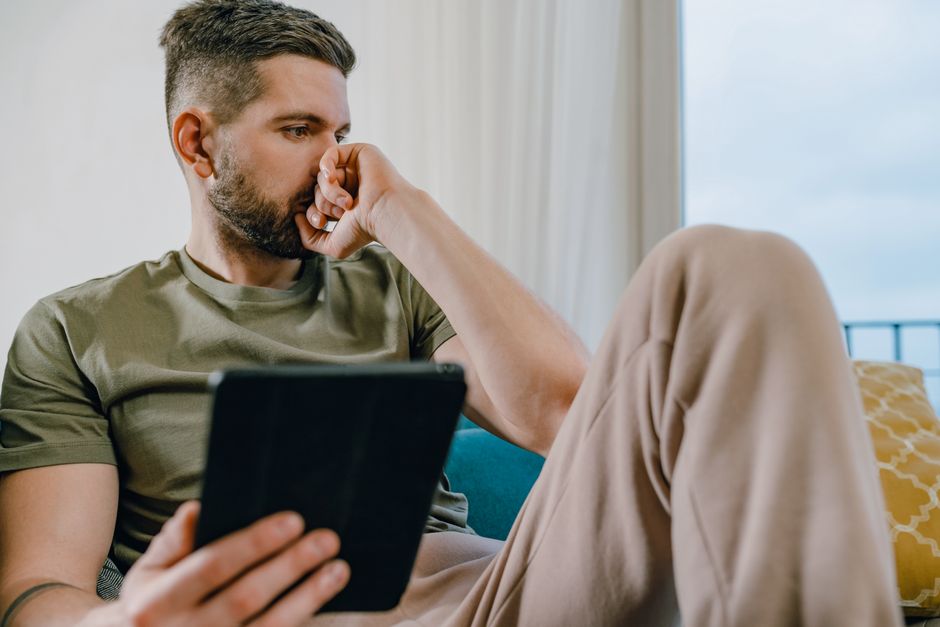 A person stands in a bright, professionally staged living room, using a tablet to review property details, representing the new, tech-savvy approach of modern real estate brokerages.